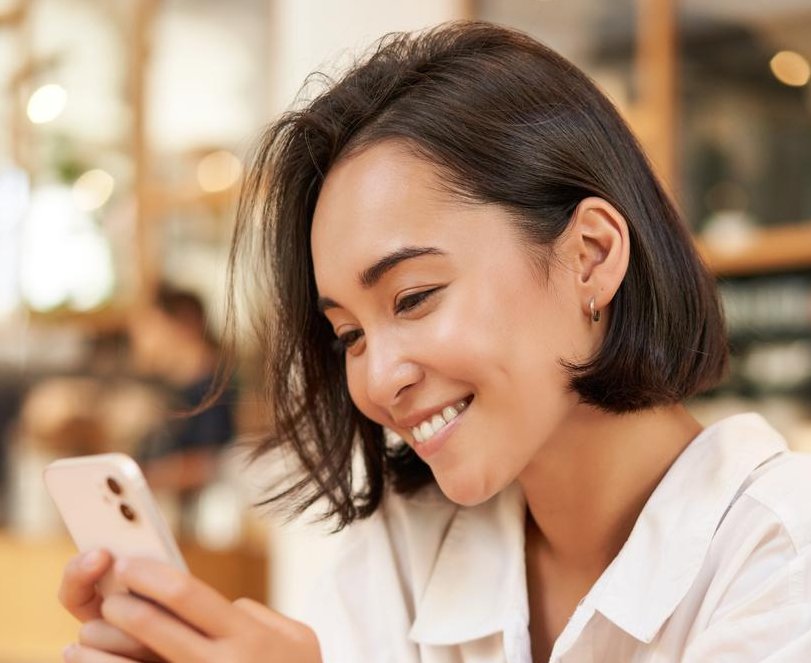 A woman in a café smiling at her phone